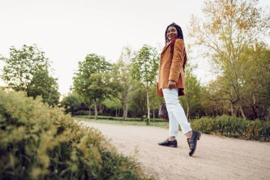 Genç Afrikalı Amerikalı kadın parkta yürüyor.