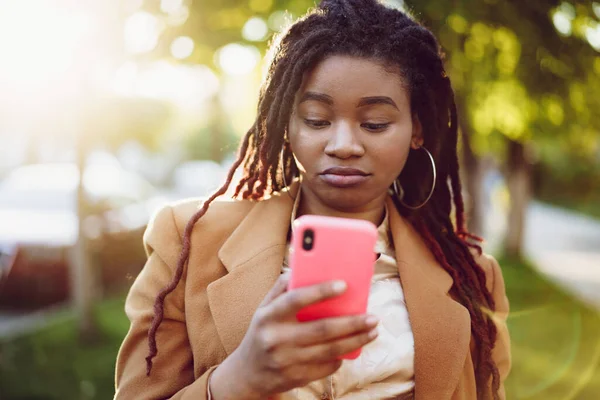 Mujer afroamericana de pie en una calle y usando un smartphone — Foto de Stock