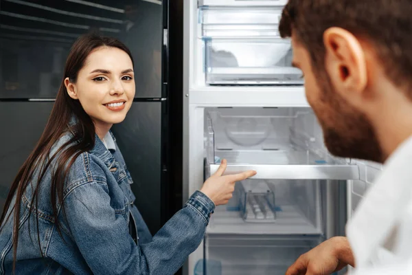 Jovem casal selecionando novo refrigerador na loja de eletrodomésticos — Fotografia de Stock