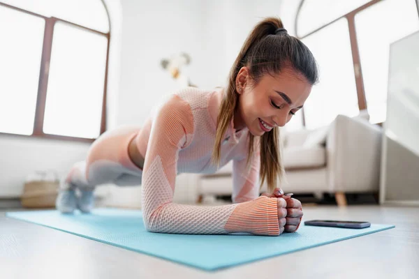 Sporty young woman doing plank exercise indoors at home — Stock Photo, Image