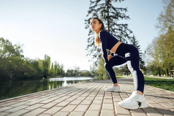 Fit νεαρή κοπέλα σε σκούρο μπλε αθλητικά άσκηση στο πάρκο — Φωτογραφία Αρχείου