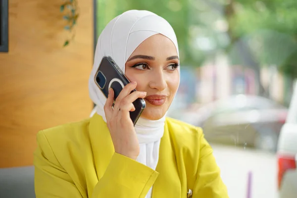 Jonge moslim zakenvrouw in hoofddoek zitten in cafe en praten aan de telefoon — Stockfoto