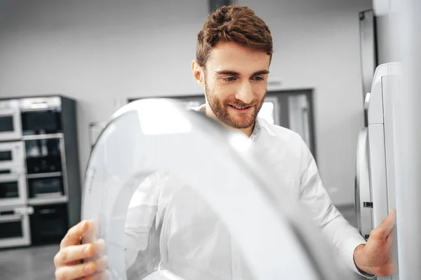 Hombre joven eligiendo una nueva lavadora en la tienda de electrodomésticos — Foto de Stock