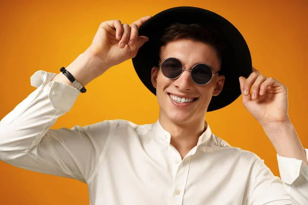 Retrato de un hombre joven y elegante con sombrero negro sobre fondo amarillo — Foto de Stock