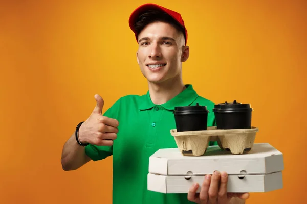 Boldog fiatal futár kezében pizza doboz sárga háttér — Stock Fotó