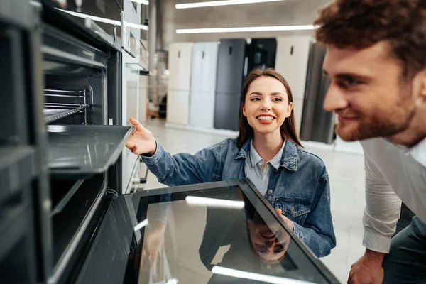 Unga par väljer ny elektrisk ugn i stormarknad — Stockfoto