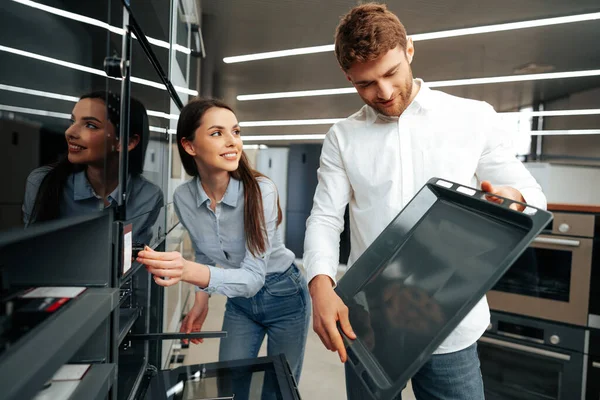 Unga par väljer ny elektrisk ugn i stormarknad — Stockfoto