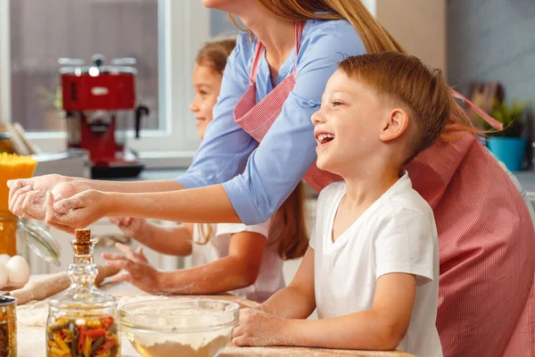 Vrouw met haar kinderen kneden deeg in keuken — Stockfoto