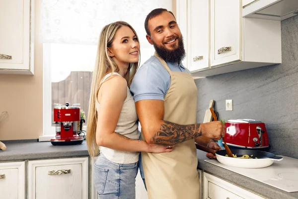 Young man and woman cooking food in kitchen together, happy couple preparing food — Stock Photo, Image