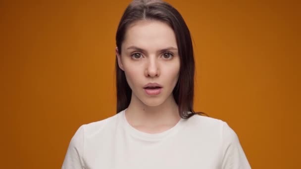 Close up of a young woman gesturing to be quiet, begging for silence, against yellow background — Stockvideo