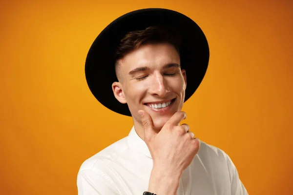 Portrait of a young stylish man wearing black hat against yellow background — Stock Photo, Image