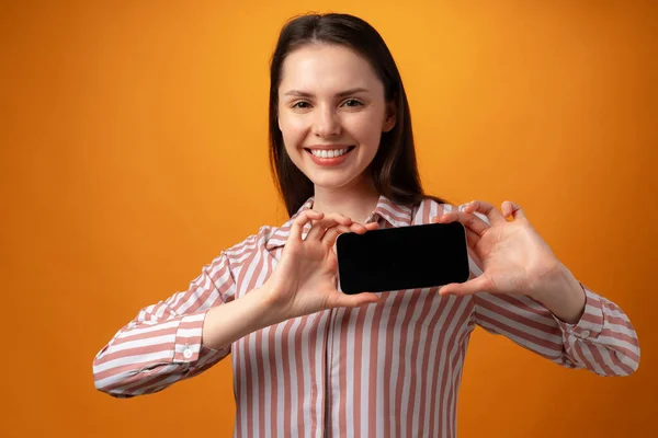 Feliz joven sonriente que le muestra la pantalla del teléfono inteligente negro con espacio de copia — Foto de Stock