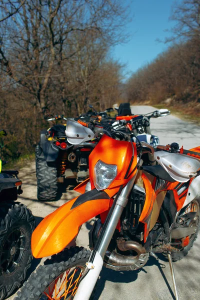 森の中の道路に駐輪されたATVとモトクロスバイクのグループ — ストック写真