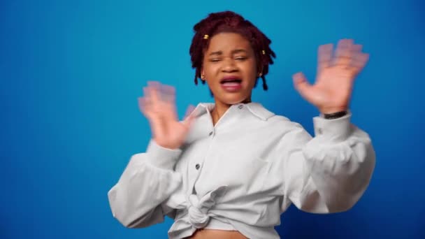 Elégedetlen afro-amerikai nő mutatja elutasítását, tagad valamit a kék háttér ellen — Stock videók