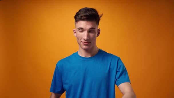 Ung man i blå uniform sätter på en mössa mot gul bakgrund — Stockvideo