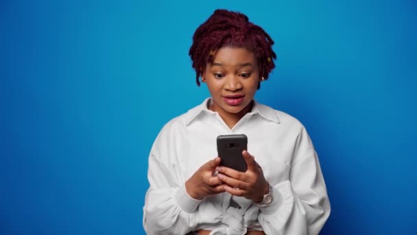 Успешная афро-женщина получила хорошие новости на смартфоне и сжимает кулак, достигла своей цели — стоковое видео