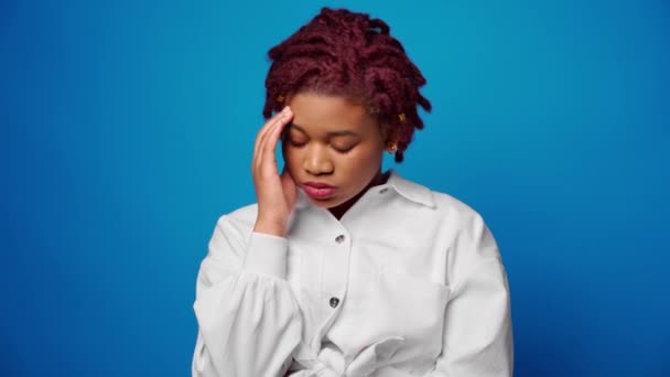 Stressato esausto afro donna che soffre di mal di testa contro sfondo blu — Video Stock