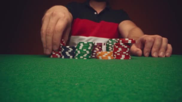 Man speler verplaatsen casino chips op poker tafel close-up — Stockvideo