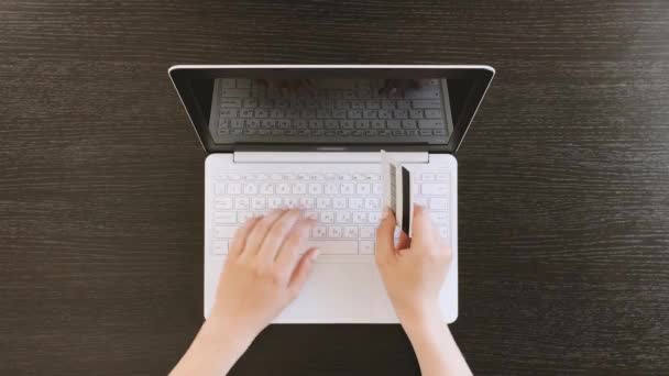 Vista superior de las manos femeninas escribiendo en el ordenador portátil en la mesa de madera negro — Vídeos de Stock