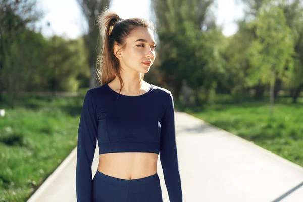 Retrato de una joven sonriente usando ropa deportiva en el parque matutino — Foto de Stock