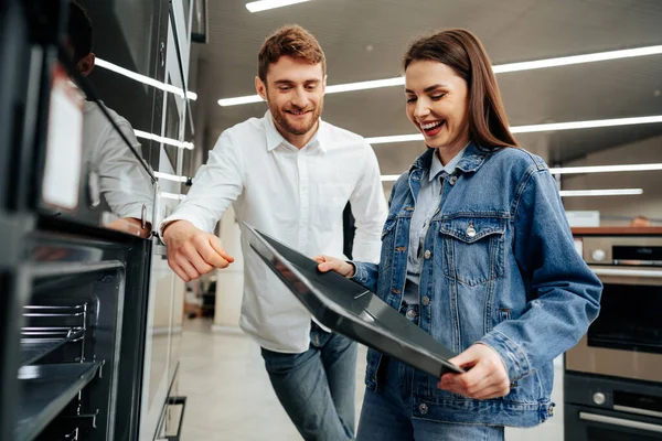 Unga par väljer ny elektrisk ugn i stormarknad — Stockfoto