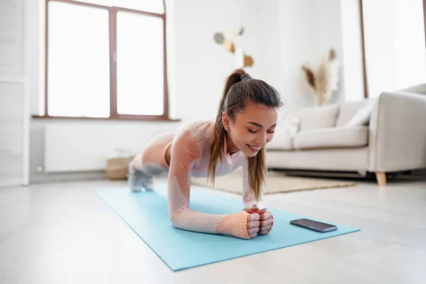 Sporty young woman doing plank exercise indoors at home — Stock Photo, Image