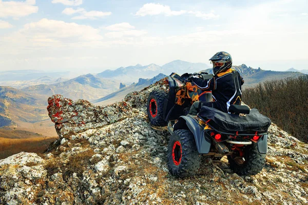 ヘルメットの男は山の中でATVクワッドバイクに座って — ストック写真