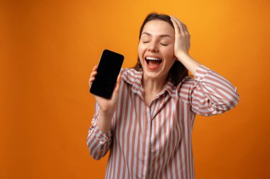 Mutlu gülümseyen genç kadın sana fotokopi alanı olan siyah akıllı telefon ekranını gösteriyor.