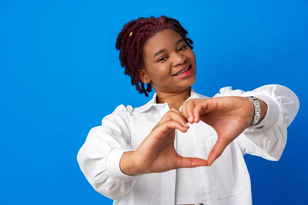 Хороша афро-жінка поклала руки у формі серця на синій фон — стокове фото