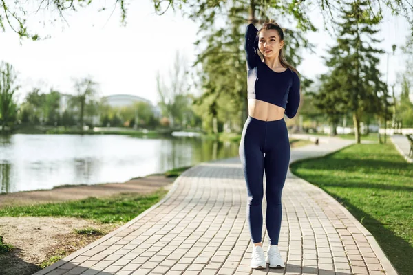 Ajuste chica joven en ropa deportiva azul oscuro haciendo ejercicio en el parque — Foto de Stock