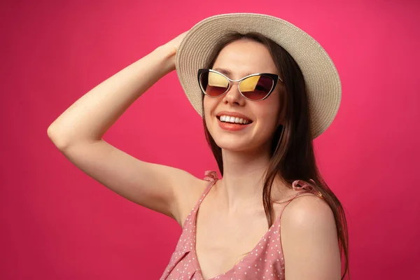 Студійний портрет молодої привабливої жінки в капелюсі і окулярах на фоні рожевого кольору — стокове фото
