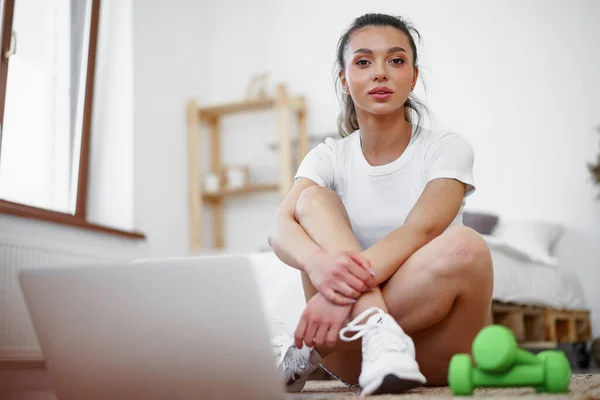 Mujer joven en ropa deportiva utilizando el ordenador portátil para ver tutoriales de vídeo de entrenamiento en casa — Foto de Stock