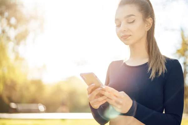 Mujer joven enciende la música para correr en su teléfono inteligente al aire libre — Foto de Stock