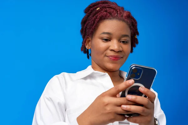 Mujer afroamericana usando smartphone contra fondo azul — Foto de Stock