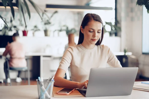 Ung attraktiv affärskvinna som arbetar på laptop på kontoret — Stockfoto