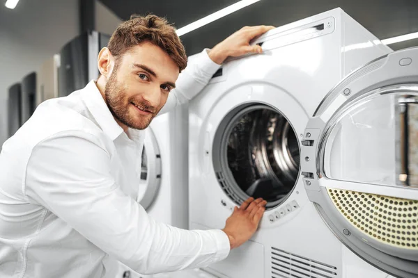 Hombre joven eligiendo una nueva lavadora en la tienda de electrodomésticos — Foto de Stock