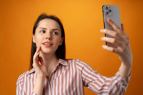 Retrato de mujer joven y atractiva usando su teléfono inteligente sobre fondo amarillo — Foto de Stock
