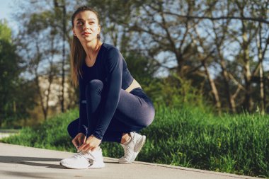 Spor ayakkabılarını bağlayan genç bir kadına yakın durun.