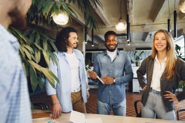 Ofis toplantısında birlikte çalışan, gülümseyen çok ırklı iş arkadaşları.