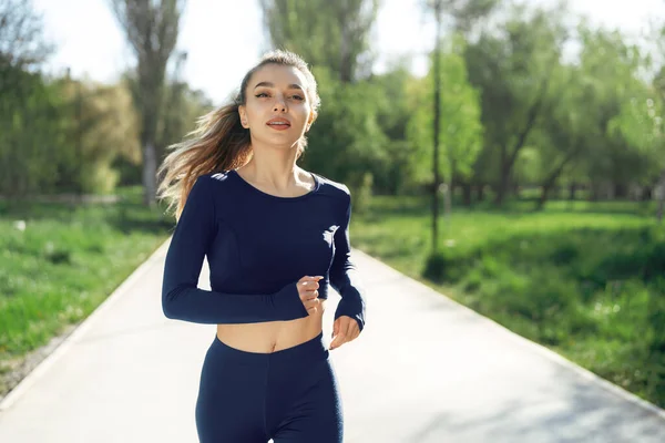 Atlético en forma joven mujer corriendo temprano en la mañana en el parque — Foto de Stock