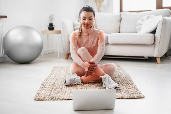 Young woman in sportswear using laptop to watch workout video tutorials at home — Stock Photo, Image