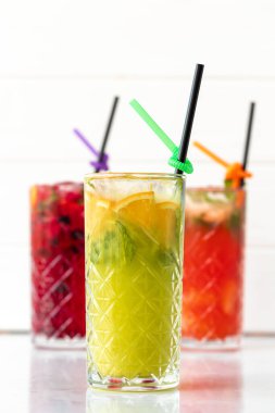 Beyaz ahşap arka planda üç farklı ferahlatıcı limonata.