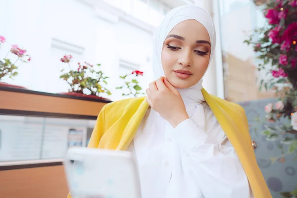 Jonge moslim vrouw in hijab met behulp van haar smartphone in cafe — Stockfoto