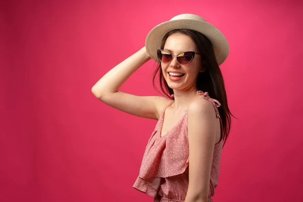 Studio fashion portrait of a young attractive woman in hat and glasses against pink backgorund — Stock Photo, Image