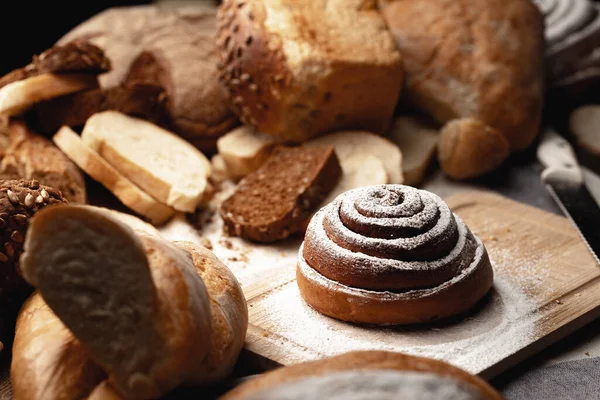 Verse kaneelbroodjes met suikerpoeder op houten plank — Stockfoto