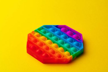 Renkli anti-stres oyuncağını sarı arka plana yerleştir