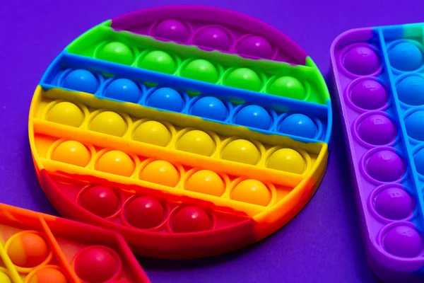 Kolorowe antystres pop to zabawka na fioletowym tle — Zdjęcie stockowe