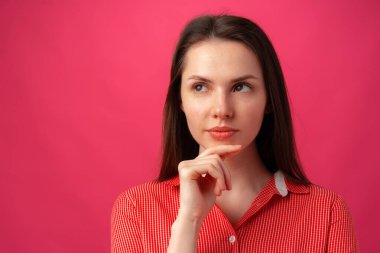 Pembe arka planda düşünen güzel bir genç kadının stüdyo portresi.