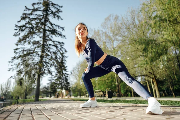 Fit νεαρή κοπέλα σε σκούρο μπλε αθλητικά άσκηση στο πάρκο — Φωτογραφία Αρχείου