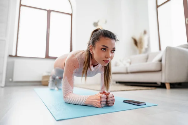 Sporty young woman doing plank exercise indoors at home — Stock Photo, Image